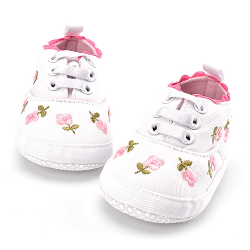 White baby shoes with floral embroidery on a white background