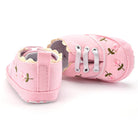 Pair of pink baby shoes with floral patterns on a white background