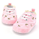 Pair of pink baby shoes with floral patterns on a white background
