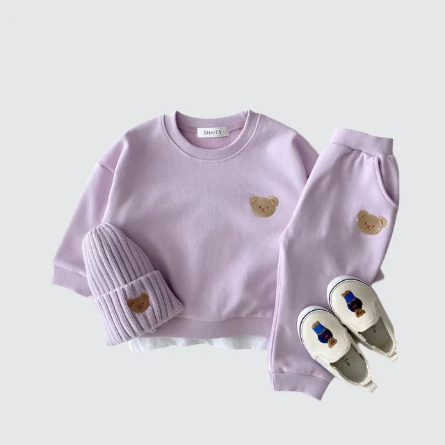 Children's purple outfit with bear embroidery on a light gray background