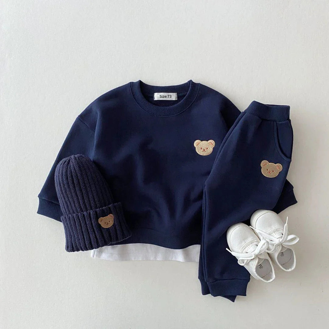 Navy blue children's outfit with teddy bear details on a light gray background