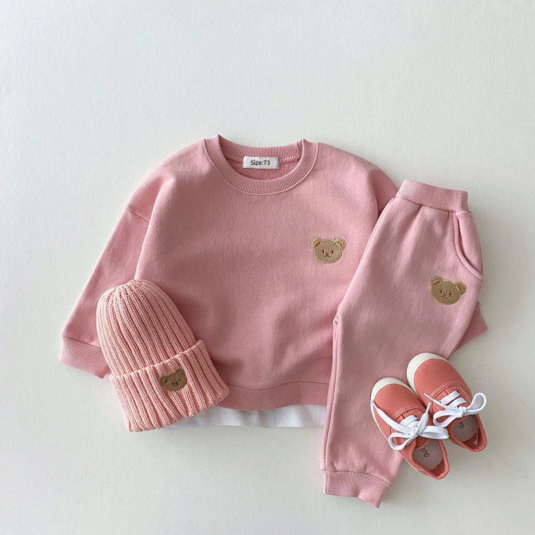 Pink children's outfit with bear details on a white background