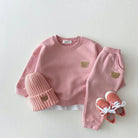Pink children's outfit with bear details on a white background