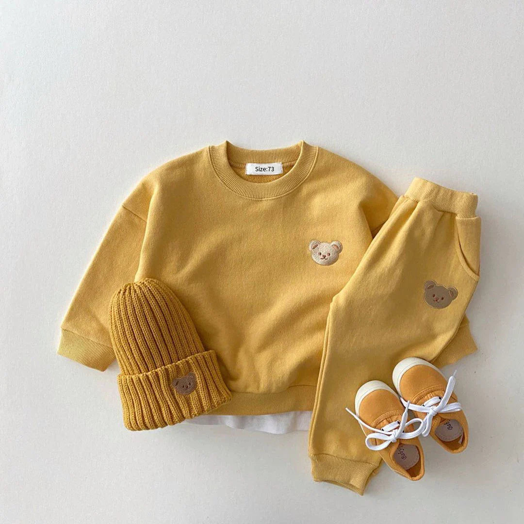 Yellow children's outfit with bear details on a white background