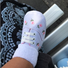 White baby shoe with floral embroidery on a bench