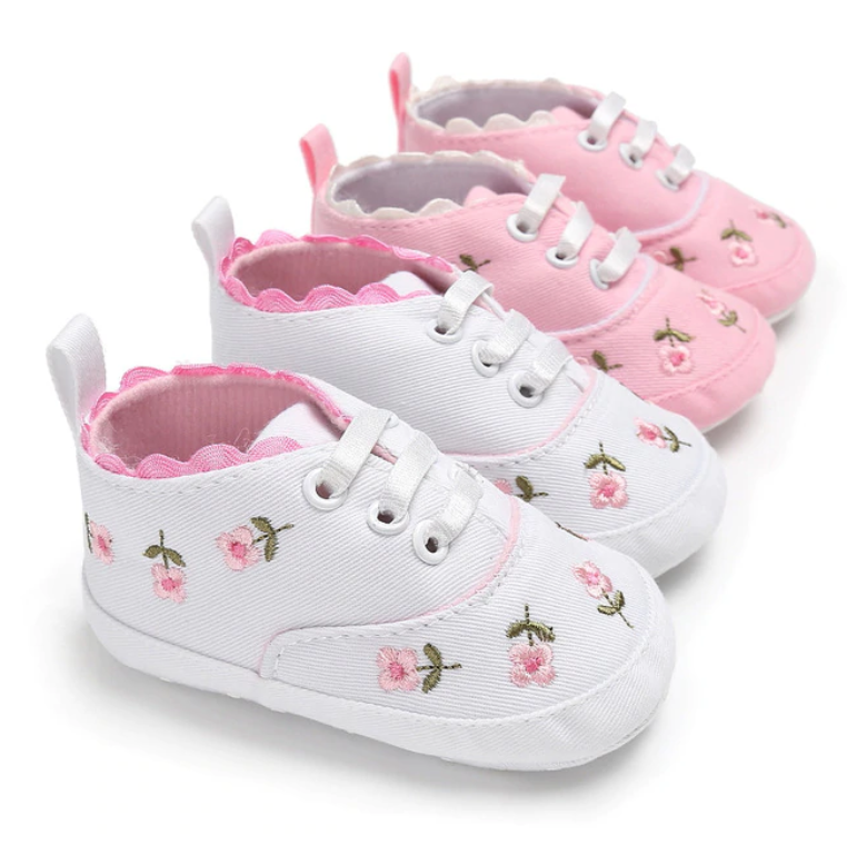 Pair of baby shoes with floral embroidery on a white background