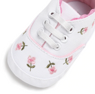 White sneaker with pink floral embroidery on a white background
