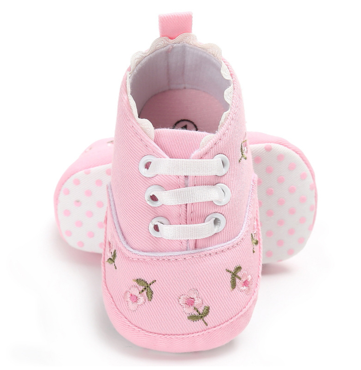 Pink baby shoes with floral embroidery on a white background