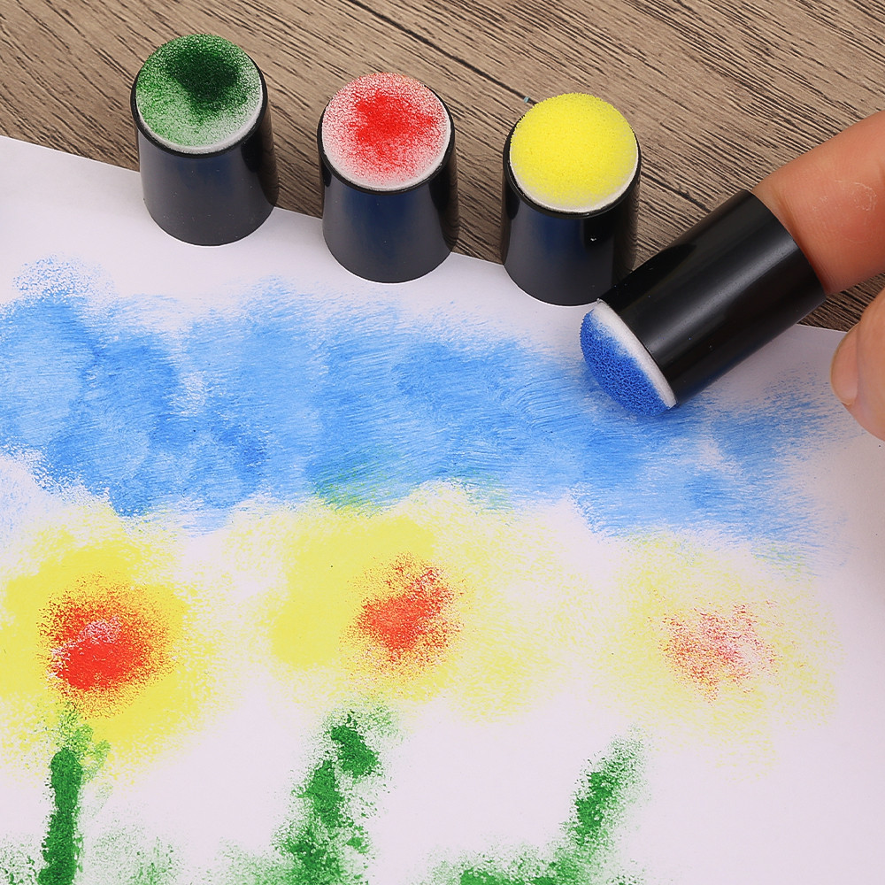 Colorful sand art with a hand holding a sanding tool on a wooden surface.