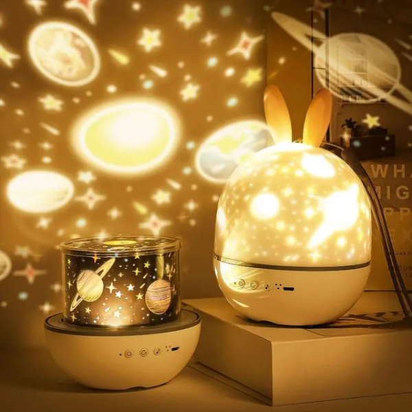 Two night lights, one with rabbit ears and the other with planetary designs, casting a warm glow on a surface.