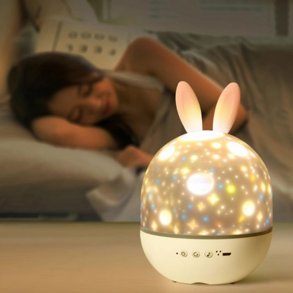 Bunny-shaped night light on a table with a person sleeping in the background