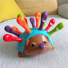 Colorful hedgehog toy with detachable spines on a textured surface.