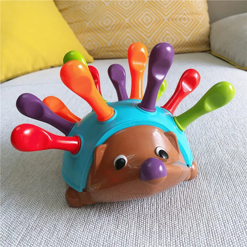 Colorful hedgehog toy with detachable spines on a textured surface.