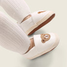 White shoes with bear embroidery worn with white socks on a light background